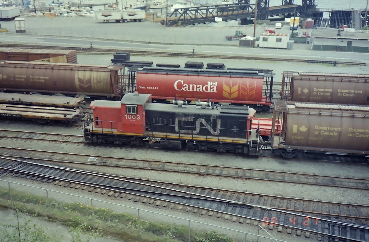 CN 1003 was the last CN locomotive used on Vancouver Island. In this 1988 photograph the CN locomotive was sitting in the CP water front yards at Vancouver BC. She had just completed her last ferry ride between Vancouver Island and the lower mainland. Soon she will be off to the CN shops in Port Mann. Glad I took my camera to work on that day, & also with me on my lunch break. Today the whole area has changed. Very trendy now!