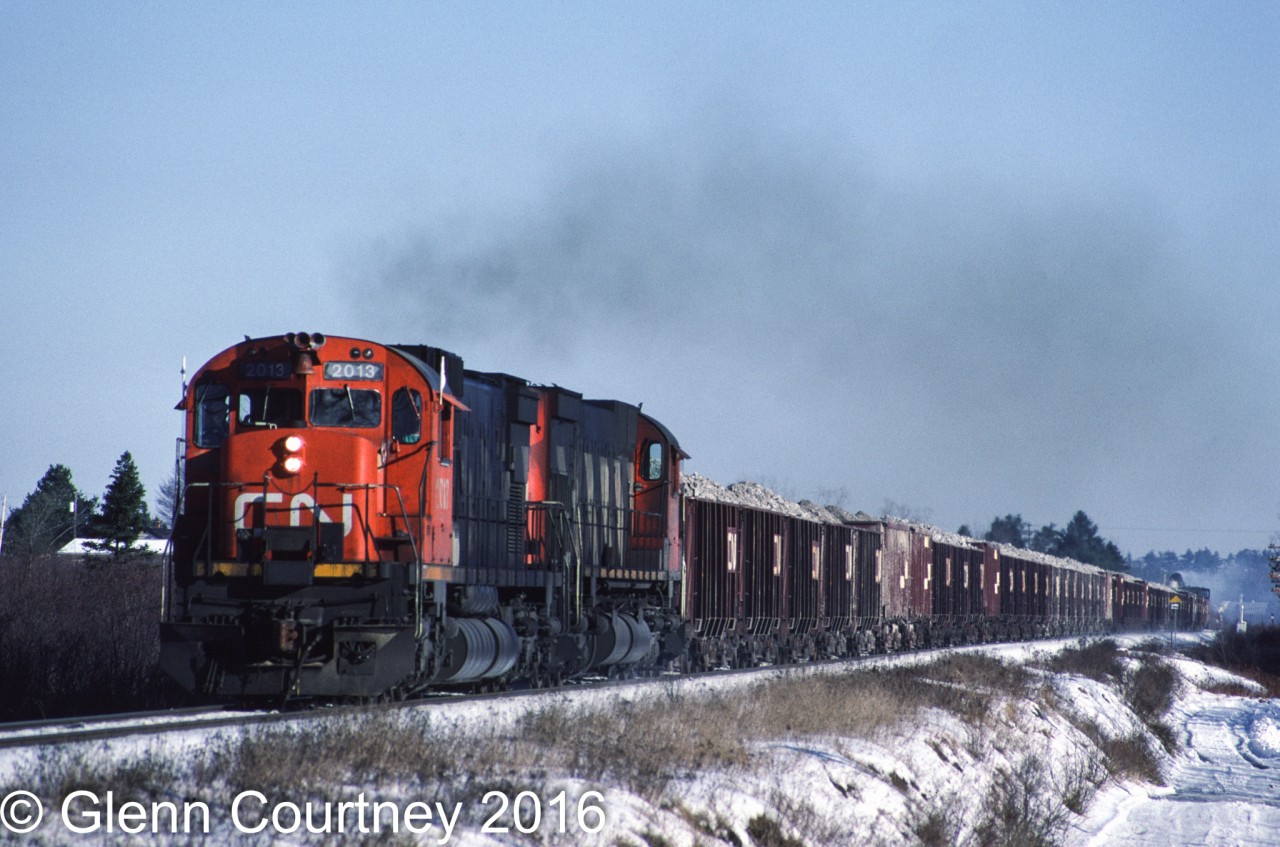 A Christmas visit back to Nova Scotia let me get out and shoot some of the weekday-only action that I rarely shot when I lived there. The main goal was the gypsum trains that ran between the quarry at Milford and the shipping pier at Wright's Cove. In 1987 you could chase and intercept the train a couple times in the 30-some miles between the quarry and Wright's Cove, not too likely you could do that today. 

Here's the loaded train with the typical locomotive consist of a pair of big MLWs trailing about 50 cars and van rolling between Elmsdale and Endfield.