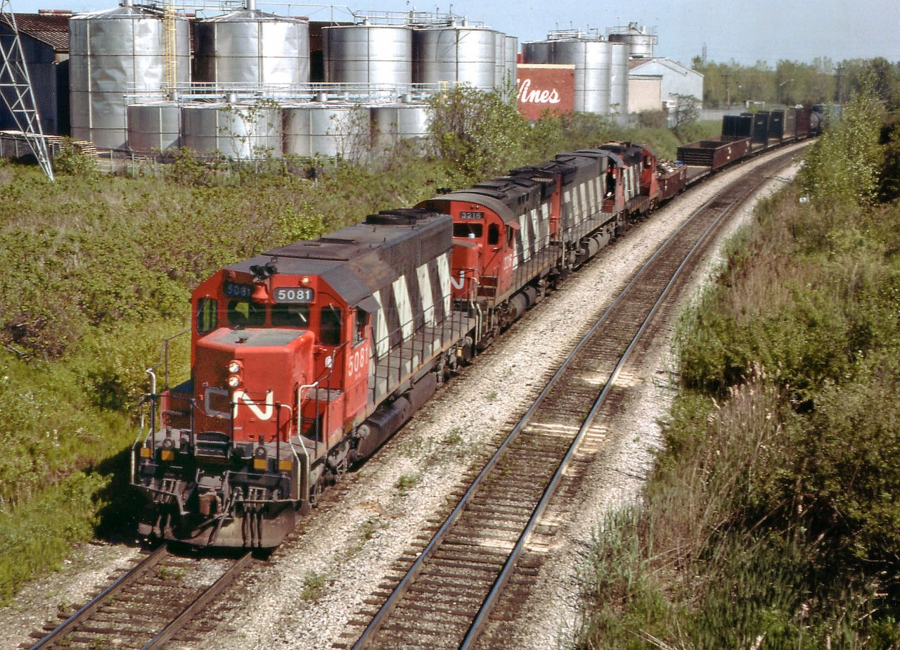 Back when there were trains to see I used this Portage Rd bridge vantage point rather often. I cannot quite make out whether that white marker to the right of the last unit is the MILE 3 marker for the Grimsby sub., but that would be about right. All those big tin cans in the background are part of the Chateau-Gai Wine empire that used to be in business there. I don't know what happened with them, but one day I went by...everything was gone and some outfit was storing lumber on the property. So that, along with all the interesting power on this westbound train, is now history. Two MLW sandwiched by GMD. SD40, a C424, an M-636 and GP9 on the rear. The GP soldiers on as CN 7032:2 according to CTG. The others all off the roster. Power consist is CN 5081, 3216, 2339 and 4533. Barely visible in the background is the corner of Whirlpool and Stanley Av.