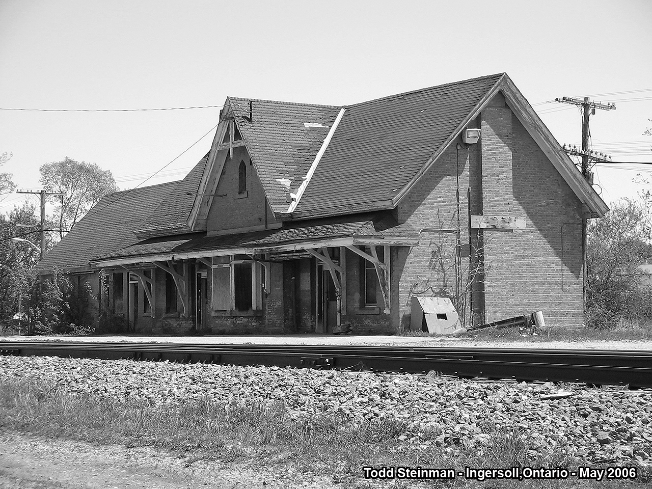 Black and white photos have always represented to me the capturing of a subject matter from years gone by. Sadly, the ex-GWR / CN station in Ingersoll shows that very neglect from the years having gone by. 
Upon my most recent trip to the station in the summer of 2014, it's state of neglect had worsened so much that thr back side of the building had almost caved in completely. A short time after, I found online that the town had talks with CN to purchase it. But like so many other stories of other town's in Ontario trying to save a piece of their architectural history - the station would prove to be too costly, as well as town of Ingersoll not being able to plan a 'further use' for it.
I am hoping that the station does still stand, and it does get saved. Anyone who lives in that area, or have made a railfanning trip to there, please keep me informed.