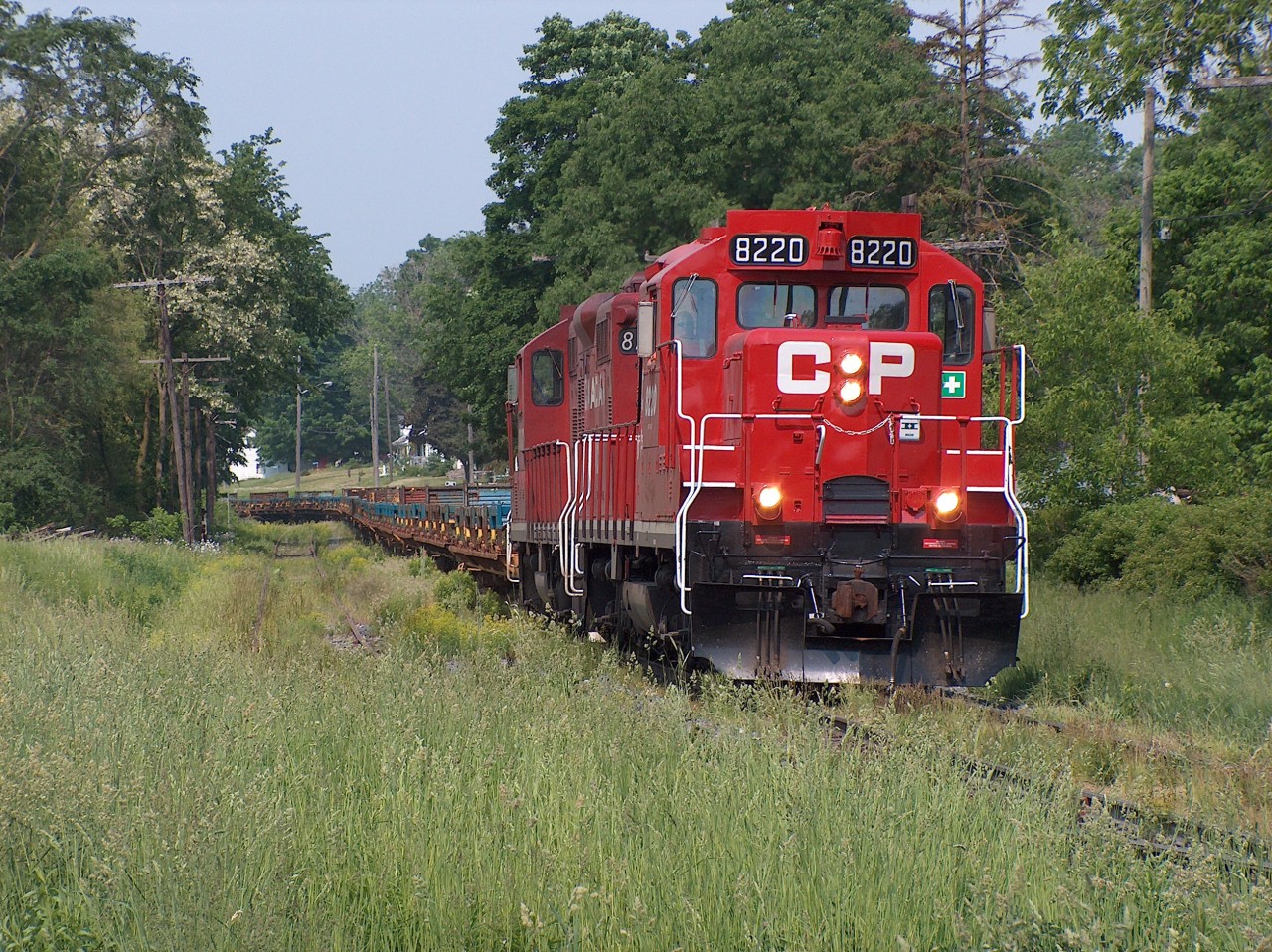On a hot afternoon in June 2007, the westbound CP frame train heads towards St. Thomas with empties. I believe its counterpart was CP 142 with loads that usually traversed the CP lines in the morning. From my knowledge, OSR did not acquire this line yet (at the time of the photo) so perhaps CP 141/142 were the only trains on the St. Thomas sub at that time (perhaps one or two other locals?). Currently, this portion of the line at Beachville appears to be a lot more active than back then; there's usually train cars in the siding and I don't think there's as much overgrowth! The train looks like its trundling along a seldom used forgotten spur. Which reminds me, the GEXR Waterloo spur was also a lot overgrown at one point (i.e. 1995) compared to its current state. It's as if these lines were on the verge of abandonment and got saved!