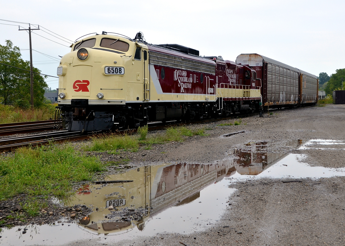 F-unit reflected in the rain. FP9A OSRX 6508 and GP9 OSRX 1620 are parked at Woodstock, with the units reflected in the rain.