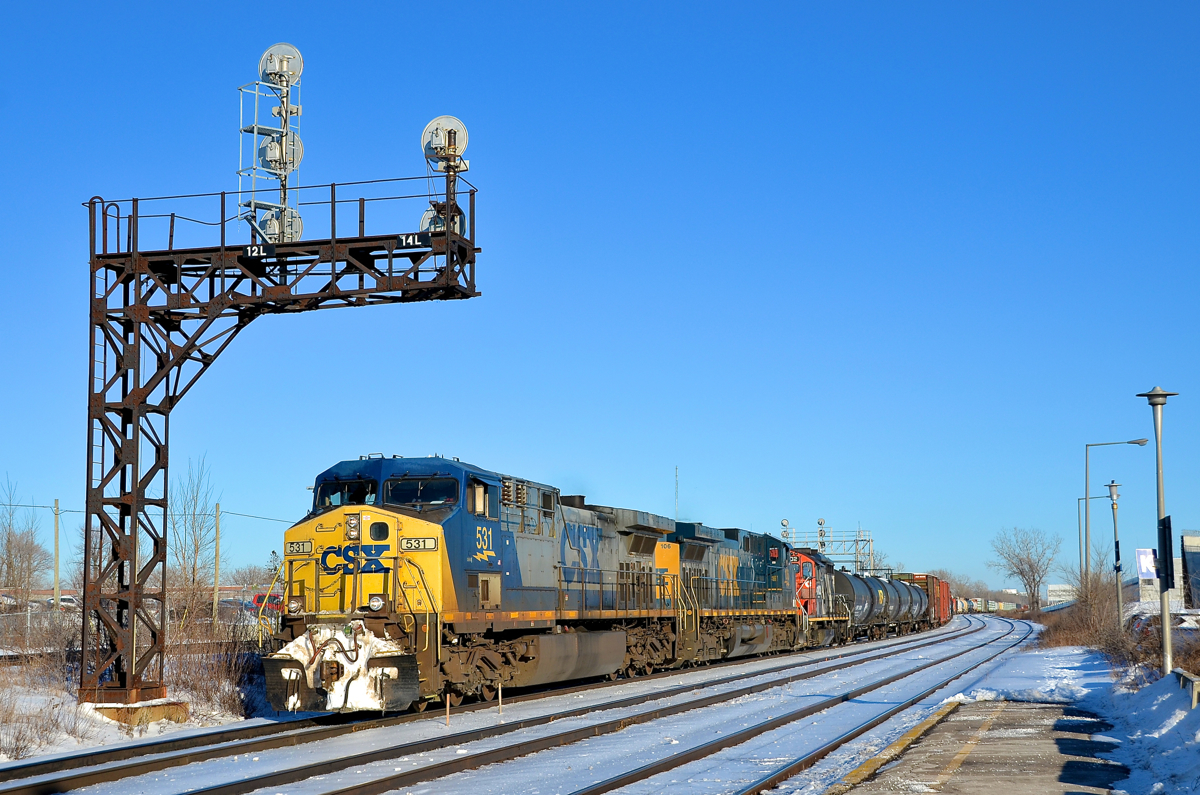 Differences in AC4400CW's. CN 327 is through Dorval on a gorgeous afternoon with a pair of CSXT AC4400CW's (CSXT 531 & CSXT 106) along with GP9 CN 4102. The leading unit is newer (built in 2001) but has the older YN2 paint scheme, while the older trailer (built in 1995) has the newer YN3 paint scheme. Another difference is the steerable trucks on the leader, versus the hi-adhesion trucks on the trailer.
