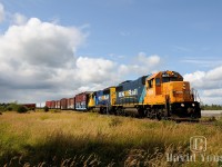 Leisurely racing the rain clouds, Ontario Northland freight 514 clicks alongside Trans-Canada Hwy #11 east of Moonbeam, Ontario embracing the harmonic rock and roll which comes along with traversing track limited to 15 MPH. 514's consist has paper loads from the Tembec mill in Kapuskasing on the headend, along with a string of freshly painted CN chip cars which came in on freight 516 from Hearst, which were interchanged off the CN Soo Sub.