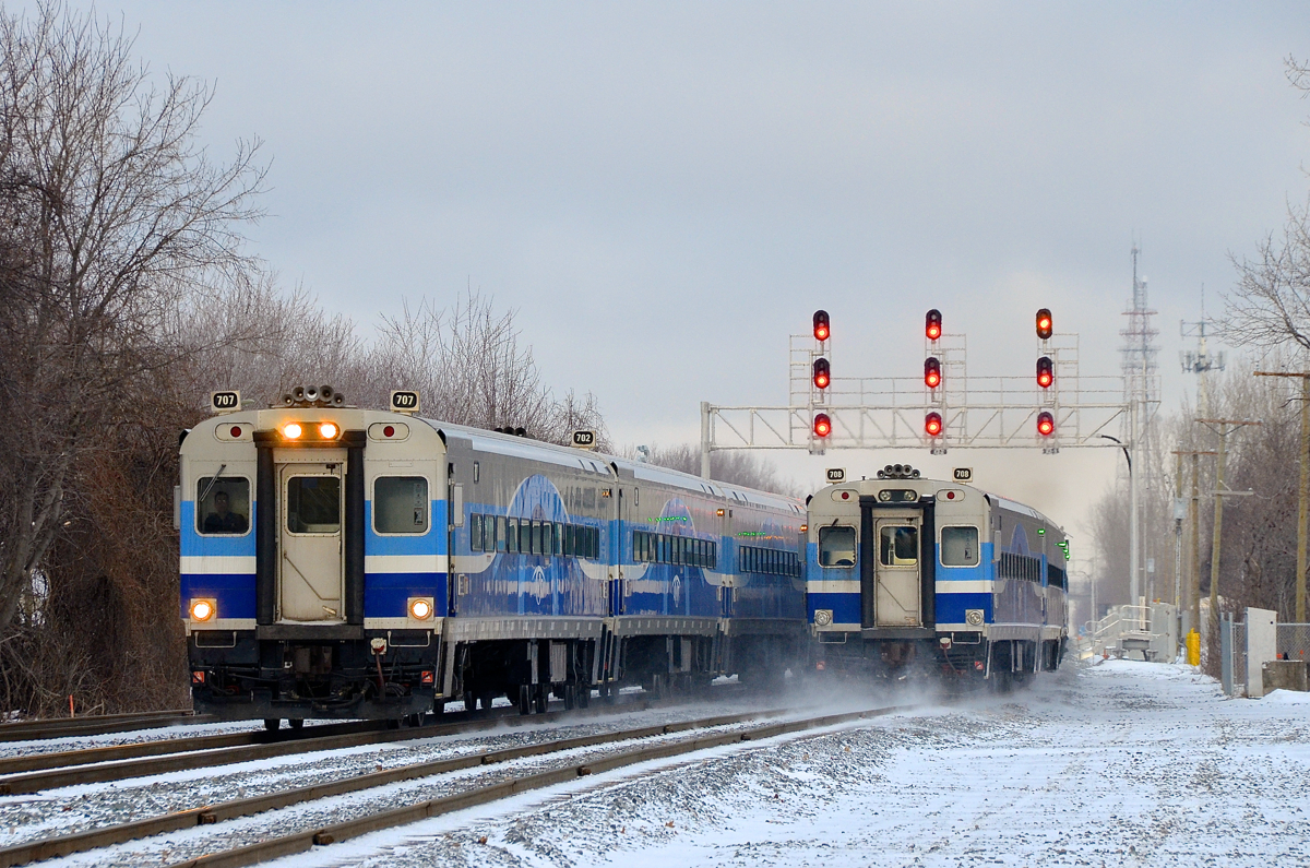 Comet cars heading west and east. At left AMT 87 for Candiac is heading west towards Montreal West with cab car AMT 707 leading. At right a deadhead move heads east towards downtown Montreal with AMT 708 at the rear. Both trains have consists of Comet cars built by Bombardier during the late 1980s.
