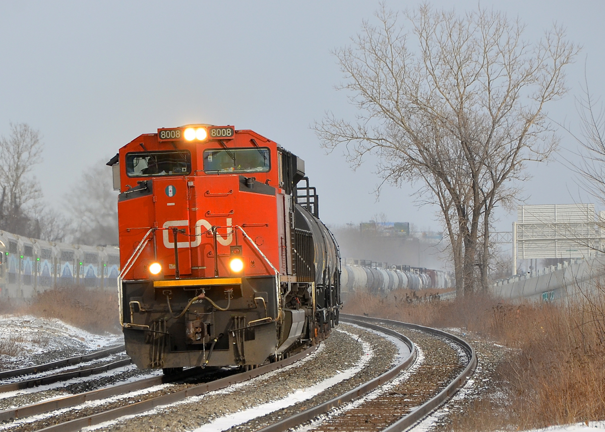 AMT east, CN west. CN 377 is heading west through Dorval with CN 8008 leading. At left AMT 24 heads east after stopping at the AMT Dorval station.
