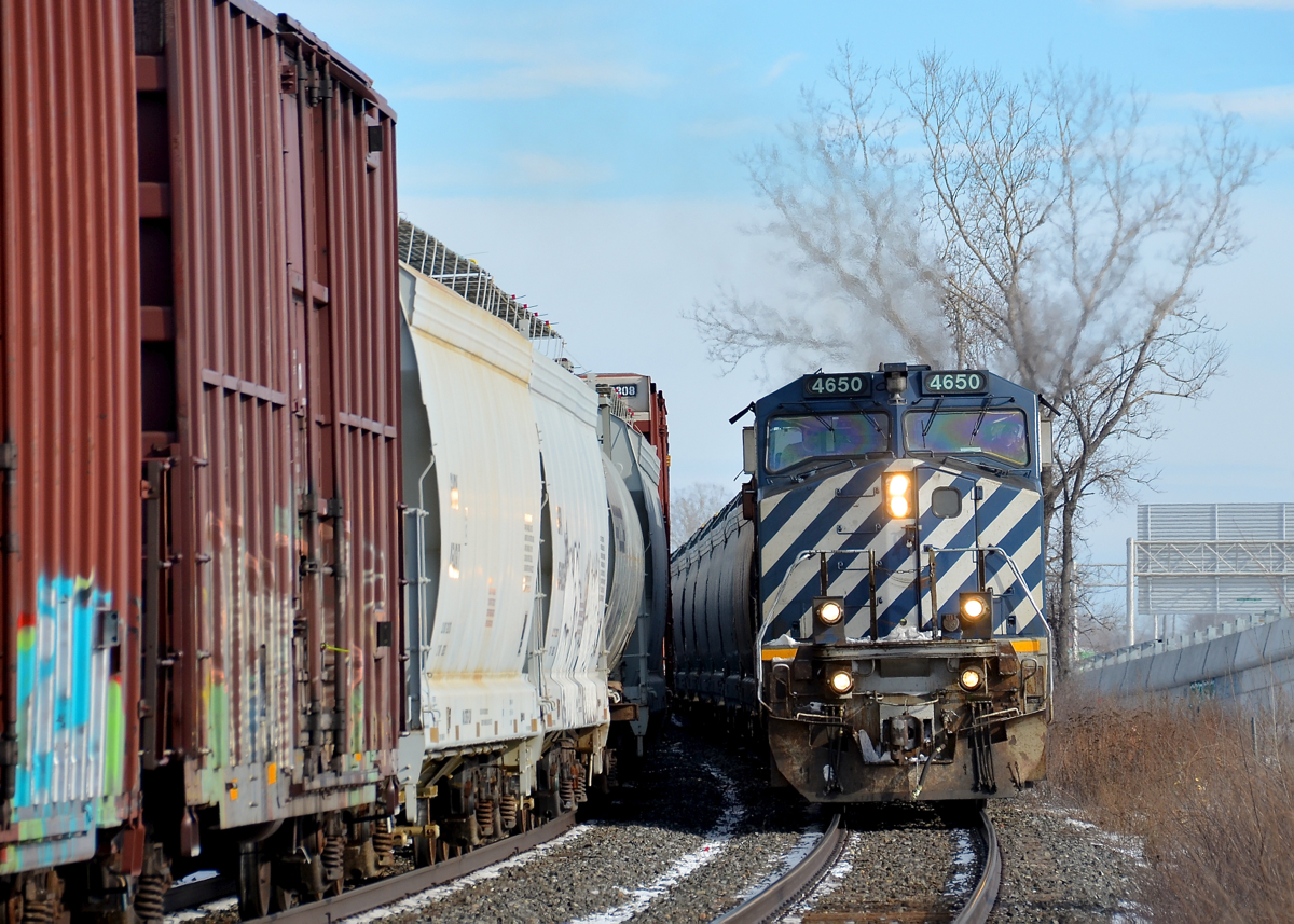 CN 368 and CN 377 around a curve. CN 377 heads around a curve in Dorval with BCOL 4650 leading on the south track of CN's Montreal Sub, as CN 368 heads east on the north track. Note: shot with a telephoto lens from the VIA Rail station platform
