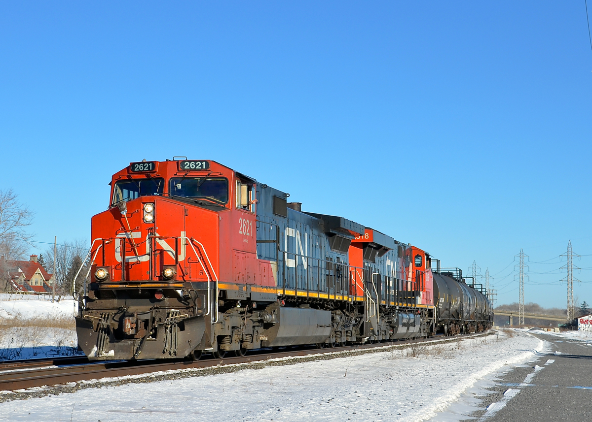 A wave from the conductor. GCN 377 with CN 2621 leading is rounding a curve in Sainte-Anne-de-Bellevue, as the conductor waves. Trailing is CN 2318.