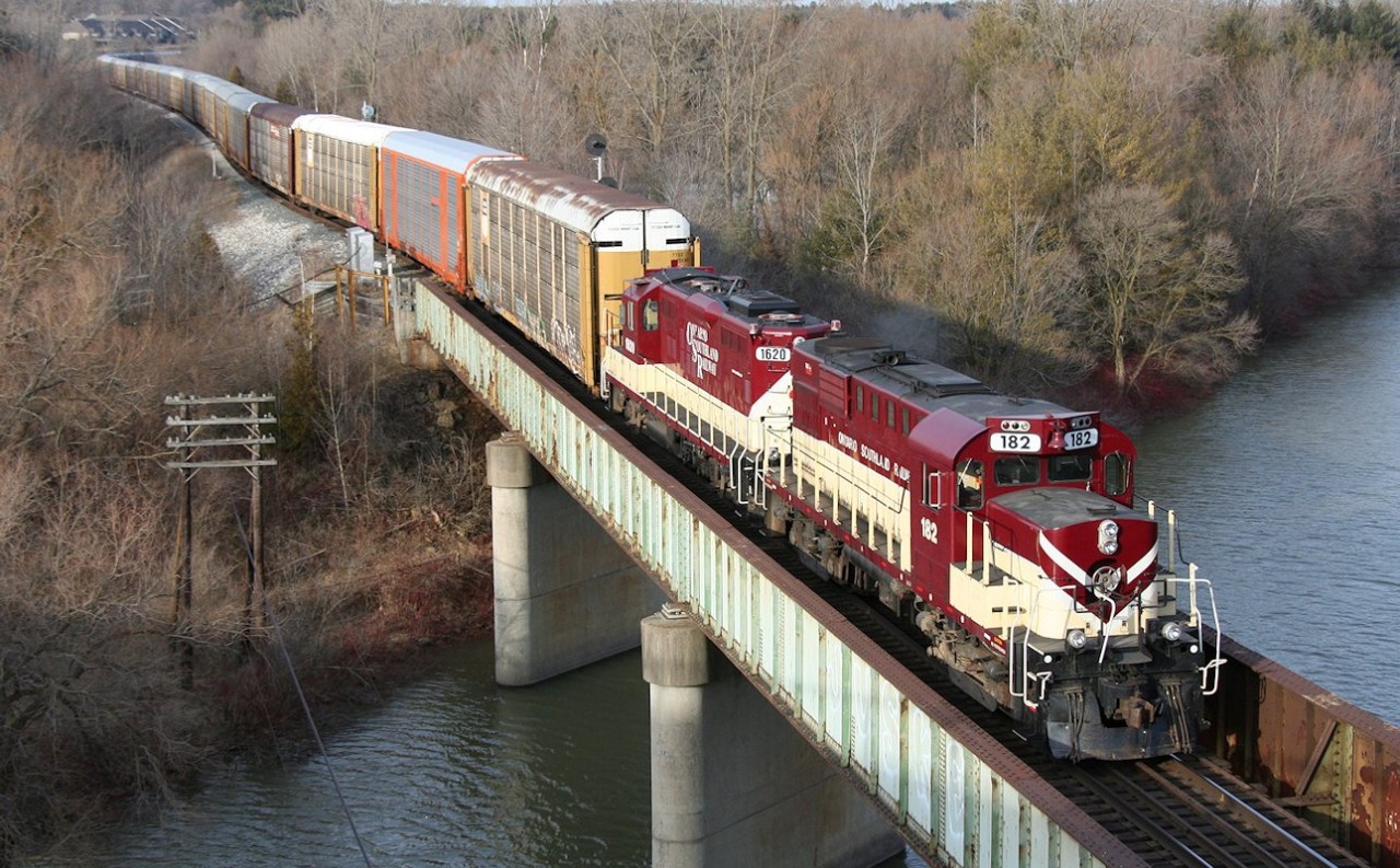Ontario Southland's daily interchange job trundles across the Thames River with RS-18u 182 and GP9u 1620 and a sizeable string of empty auto racks for the CAMI plant in Ingersoll.