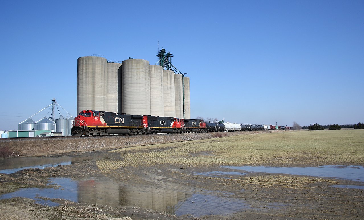 Dwarfed by the massive Wanstead Co-op grain elevator complex, CN 2547 leads a westbound freight heading towards Sarnia.