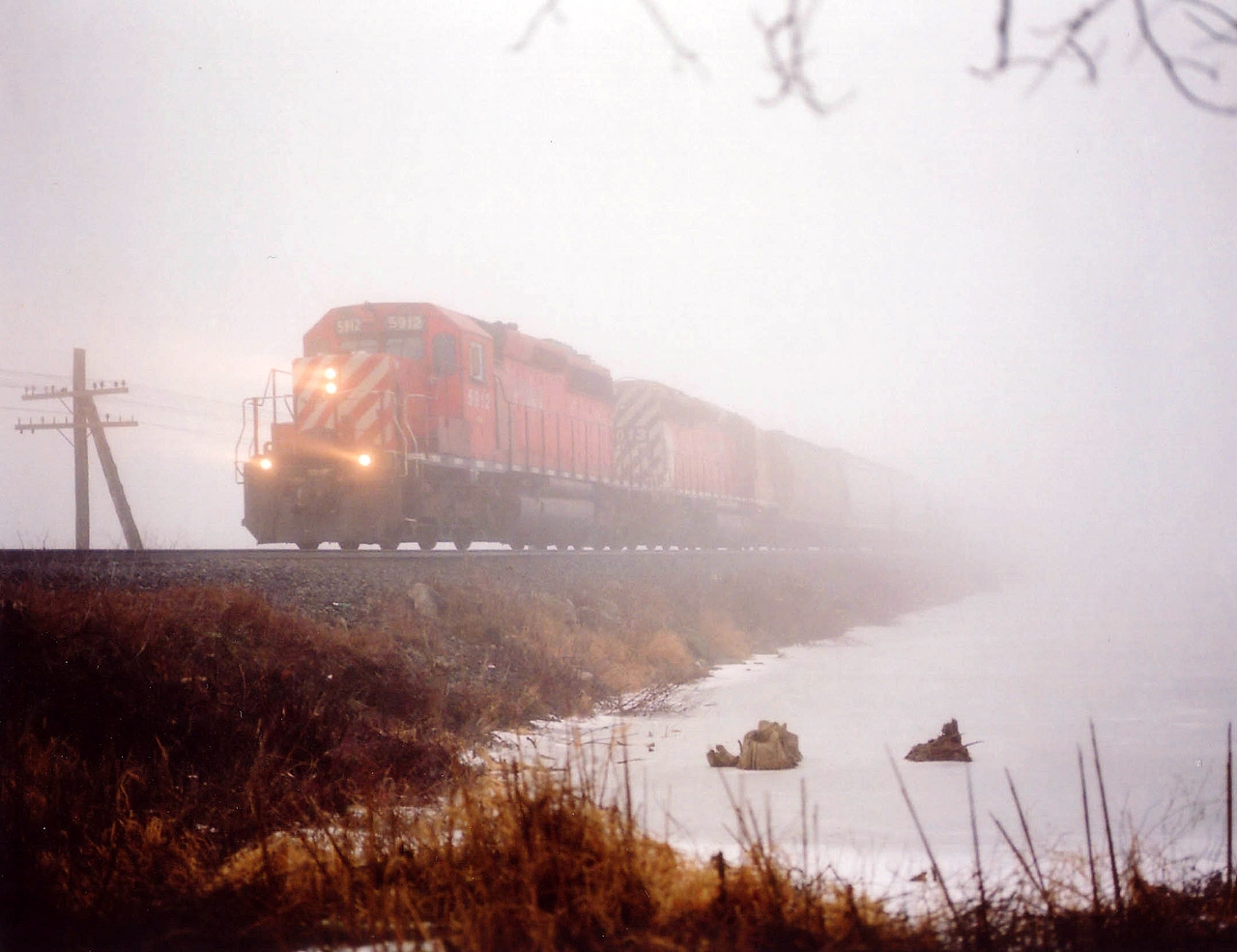 Just one of those days in which I wanted to go out no matter how crappy the weather. CP was still running 3 westbounds each morning between 0830-1230 and one of them, #441 was habitual with its SD40-2 locomotives for power. My prime target. This, after so many years of being 'tired' of them..........
I parked at the west side of Mountsberg Conservation area and walked down across the frozen stream, past the dam, to the railway where it crosses the reservoir and waited it out at the waters' edge. I have minimum 10 minutes warning usually when trains call Guelph Jct for permission west. This is a great location in good weather, but it IS an area in which an entrance fee is charged. NOT advisable to walk in from the closest sideroad. Anyway, out of the fog comes CP 5912, 6013 as #441 west. I've got a image with some mood to it, and am satisfied. Not long after this, #441 was abolished. Now, it is hit and miss to see anything along here, as most of the local fans know.