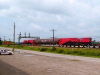 The world's largest rail car, the 740,000 pound Schnabel CEBX-800, with a load consisting of a 675 ton reactor; waits out traffic at Paris Jct before proceeding west on a week long trip to Kansas. This thing is huge; 36 axles; and over 2 million pounds with this payload. CN train #560, with CN 5528 the sole power is on its second day from Oakville, and was to be in London during the overnight. Security was present all along the move, (note the cruiser) although I was able to get permission for some photos from up on rail property of trains passing alongside this monstrous beast. I liked this photo because it gives a good idea of just how big this railcar is.