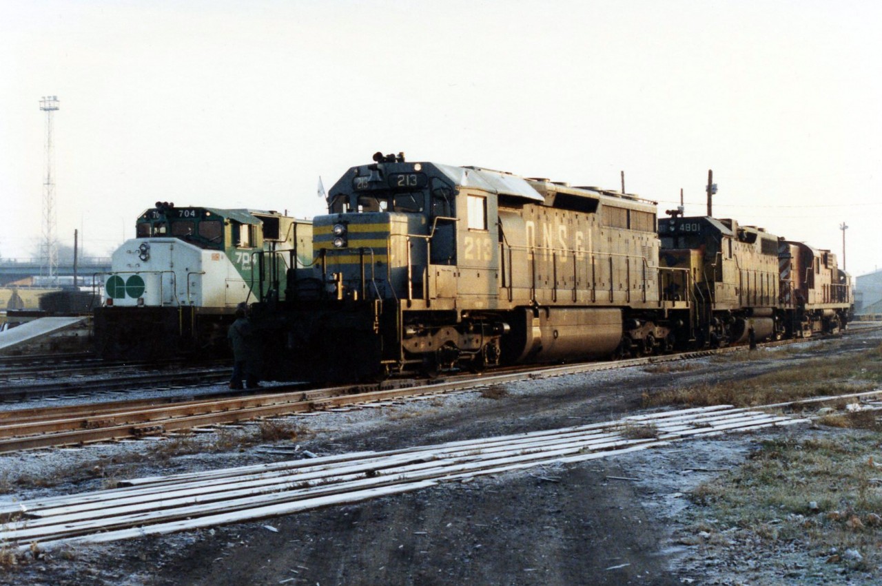 A weekend worrier GO GP40-2W 704 shares the shop tracks at Quebcec street with QNS&L SD40 213, Chessie/B&O GP38 4801 and and unidentified CP RS18 on a chili November morning in 1984. The crew is talking with the shop foremen before departing for there train.