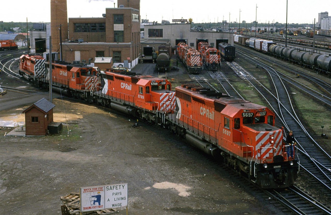 An interesting assortment of power is seen on the "serviced" side of the shops. The high-nosed GEEP will likely be the power on the "Exshaw Turn". A VIA F B unit sits and waits to be called upon. There are some awfully bright lights on the rear end of a caboose in the yard. I presume that the tank car beside the shop is delivering heating fuel, or fluids for the locomotives. 
...and don't you love the sign at the bottom of the photo.