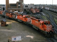 An interesting assortment of power is seen on the "serviced" side of the shops. The high-nosed GEEP will likely be the power on the "Exshaw Turn". A VIA F B unit sits and waits to be called upon. There are some awfully bright lights on the rear end of a caboose in the yard. I presume that the tank car beside the shop is delivering heating fuel, or fluids for the locomotives. 
...and don't you love the sign at the bottom of the photo. 