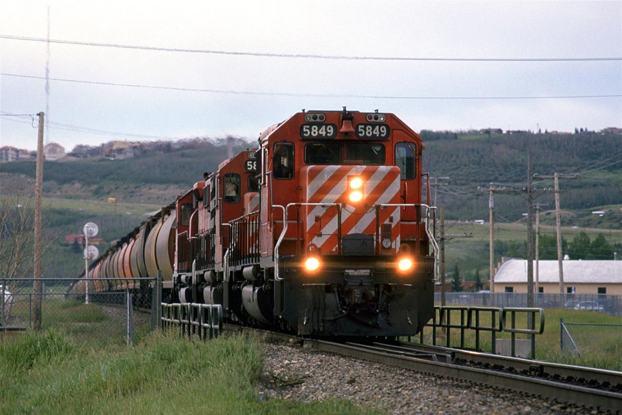 In the mid 80's there was a "Day in the Life of...." craze (for lack of a better word). This was the first railroad-related event - preceding CTC Board's first Day in the West (In a few years it would become all of Nort America) by one day. Someone in St Catherines of Welland was organizing the event and asked photographers to make submissions. I sent is several shots that I had taken that day, but nothing ever became of the project. Nor were my slides ever returned to me. I am still rather ticked.
So, this is a shot that I did not submit, of a westbound grain train approaching the high point of Brickburn. The small bridge that the train is on is for the Trans Canada Highway.