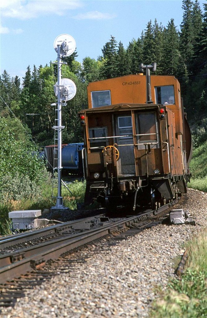 The tail end of an empty grain train passes the east switch and signal of Brickburn.