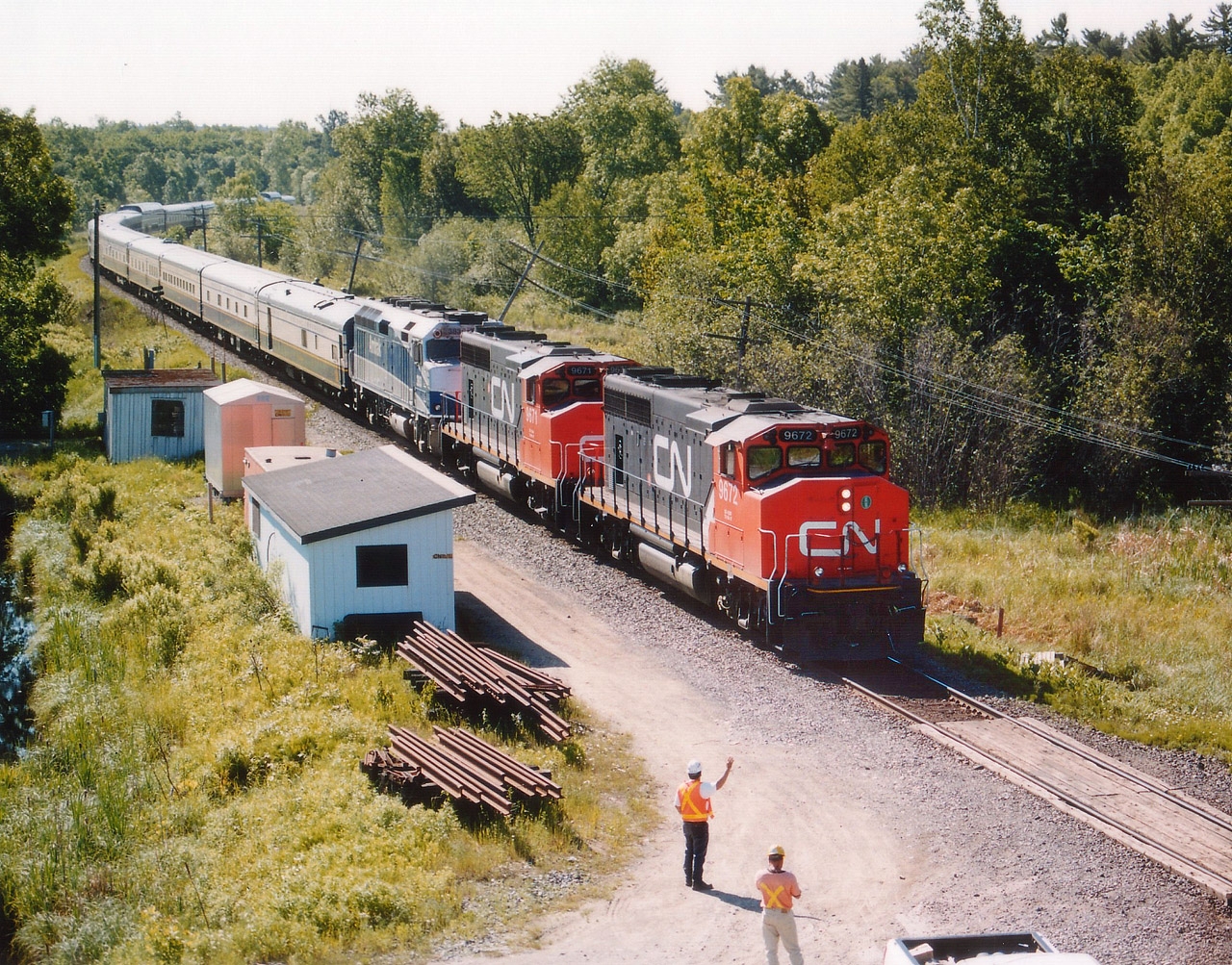 While out shooting CP in and around Parry Sound I noticed a light up on the CN for a northbound. Went over to Isabella St to wait around as I had no idea where this train might be. An old town "regular" can came up and started some chit-chat with me. The scanner crackled and I missed the transmission. A minute later, around the bend, past the station came CN and I just stepped back to watch. OMG!!! It is the American Orient Express!!!! Only the second time I had ever seen it, and again, right out of the morning sun. So I told the old guy I had to run. Hopped in the car and out onto Hwy 69 at a good clip. This train was really moving. I did not know where I would catch him so drove north until I saw the highway overpass up near Key River, some 80 KM up the road. Rather than getting mixed up in Sudbury, I elected to try for a shot here. Yelled over to a CN guy, and he told me the train "wasn't far off". I really had nowhere to wait but down by the car, as the bridge is not all that spacious (no sidewalk) and the truck traffic heavy. Figured I would hear something. I did, but almost too late. Ran like crazy, and just got to where I wanted to be with, seriously, not a second to spare. Looked down, saw the CN guy put his arm up to wave, and snapped the shot. I could have waited another maybe one second but....this was a lot better than missing it. Again, right out of the sun, but ten times better than at Parry Sound. Grabbed a couple of "going shots" off the other side of the bridge and then headed to Sudbury. But he beat me by a long shot, I was stuck in traffic. This was the last time I ever got to see the AOE. It was in business as luxury rail travel, beginning in 1989, but never really took off and became part of "Grandlux Express" and went bankrupt. August 28, 2008 it was all over. Equipment sold or scrapped.
The contract for power was with Amtrak, which is why you see AMTK 393 behind host CN 9672 and 9671.