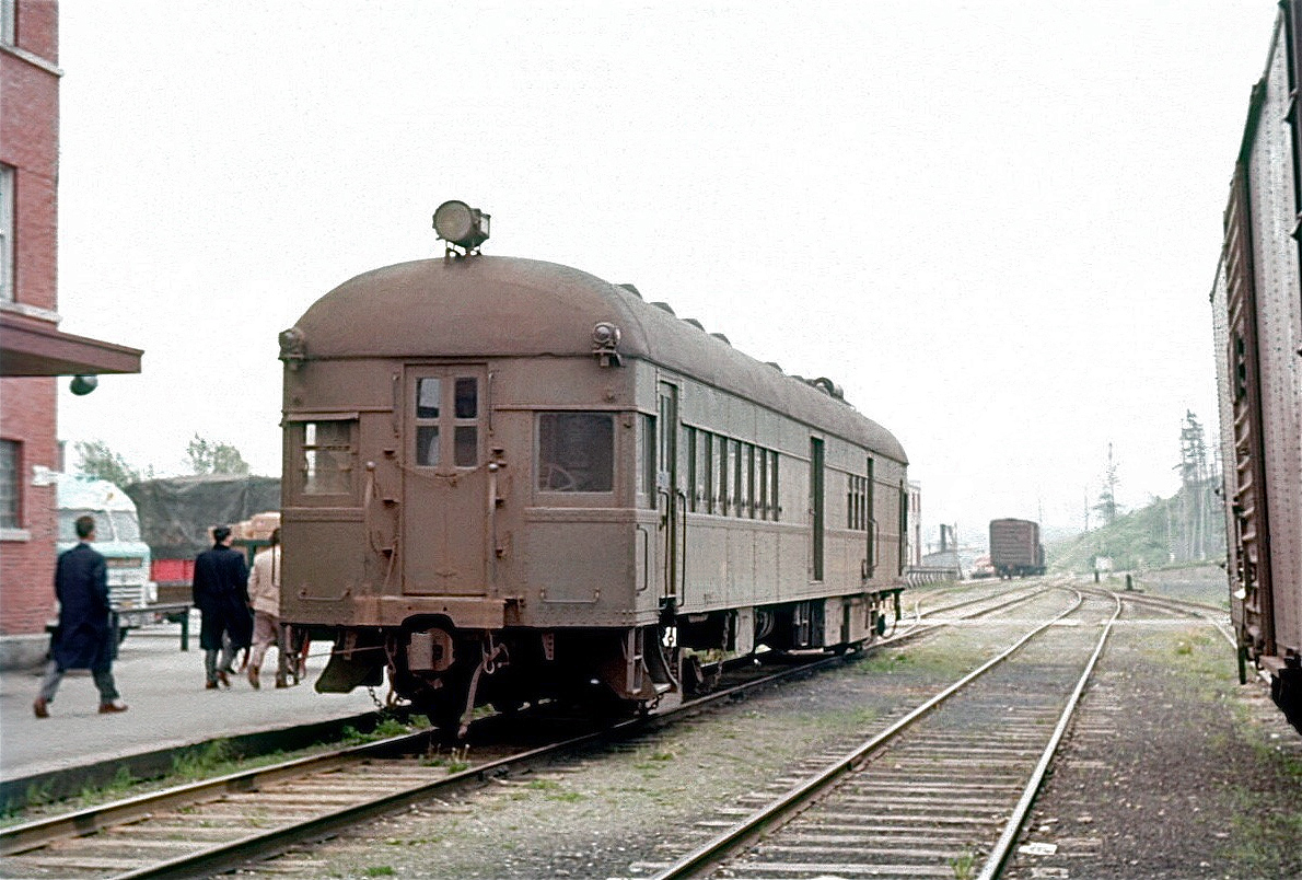 Canada & Gulf Terminal Railway diesel-electric car 405 is loading passengers on June 25, 1955 at Matane, Quebec for its 36.2 mile trip back to Mont Joli where it connects with CN trains bound for both Montreal and Halifax. 405 had been acquired from the New York Central – the yellow step stool used to assist passengers boarding still bore the NYC logo. Built as a gas-electric car, a Cummins diesel engine was substituted for the gas engine at the C&GT shops. On occasions when the traffic warranted, 405 could haul a lightweight coach. When C&GT passenger service ended in the 1960s, the car found its way back to a tourist railway in the north-eastern United States.  [Geotagged location not exact]