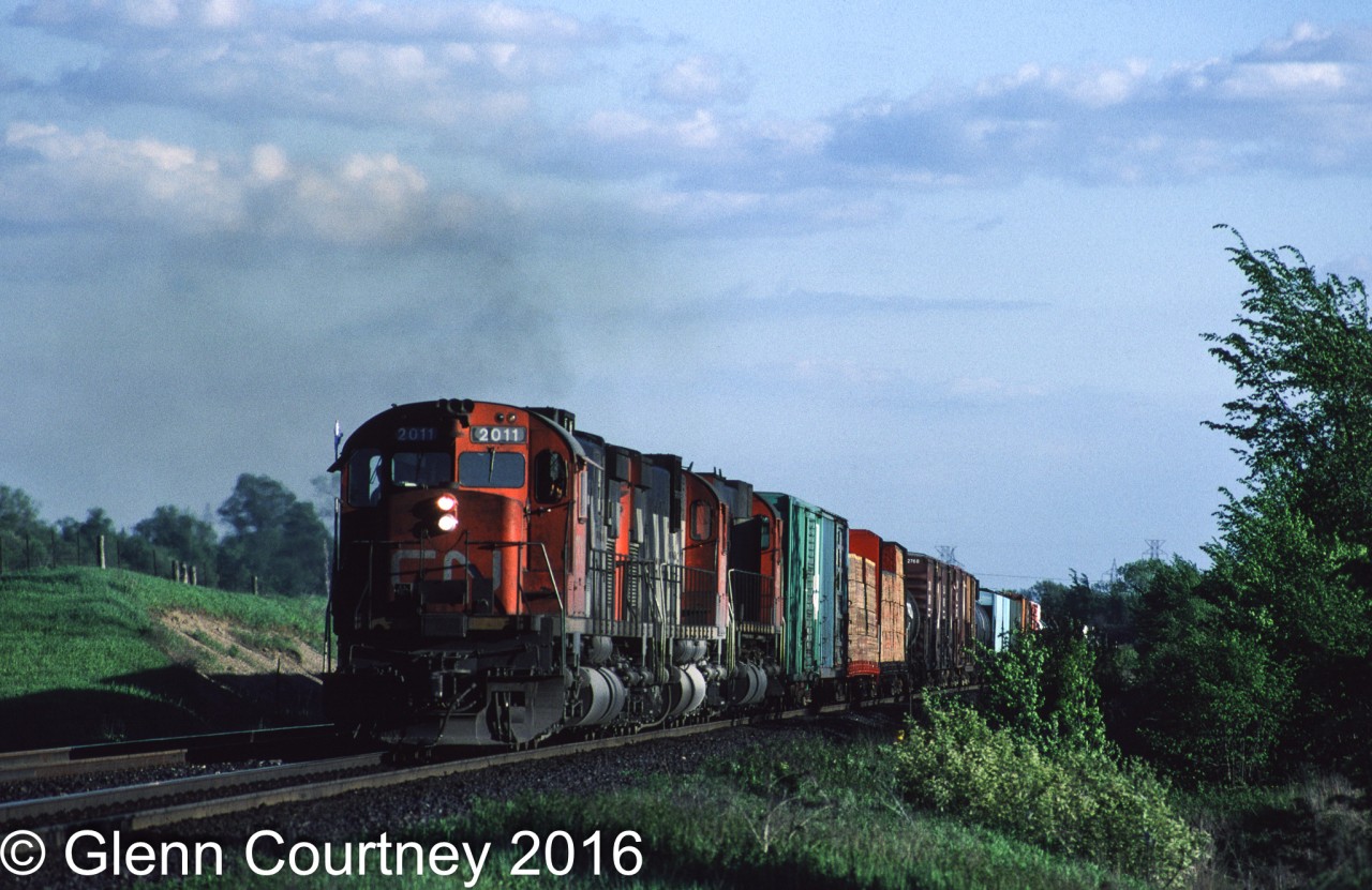In the late '80s, when I lived in Hamilton and spent a lot of summer evenings on the Laking Gardens footbridge watching trains at Bayview #392 was often seen heading east. Some nights I might just watch it past but a three-unit set of MLWs would get me onto the 403 heading for Burlington where the Halton Sub heads north putting the sun on the front of an eastbound. On this evening #392 was definitely worth the chase! Here it is struggling up the eastbound grade out of Burlington.