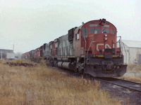 It was early in the morning when I visited the CN roundhouse area in London Ont. The area was enveloped in a heavy fog at the time. I was standing west of the roundhouse/yard office when I noticed some movement immediately south of the roundhouse. By pure luck I caught CN 2015 & CN 2031 dropping off a string of retired MLW yard engines. The MLW unites were CN 8221,8208,8232,8210,8219,8218,& 8229. They sat there for a few years, & I managed to photograph them more than once while visiting London my home town. If you grew up near Wellington & Bathurst Streets, rode the L&PS, you must be a rail fan!