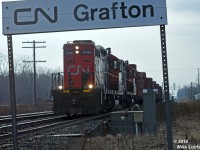 Having completed work in Cobourg including spotting seven loads and pulling five empties from a lumber customer, as well as lifting a bad order covered hopper for the carmen in Belleville to tend to, and waiting for a few pesksy VIA trains and CN 369 to clear, CN 7000 and 4136 accelerate 518's train off track one and past the station name sign at Grafton, Ontario. 1623hrs.