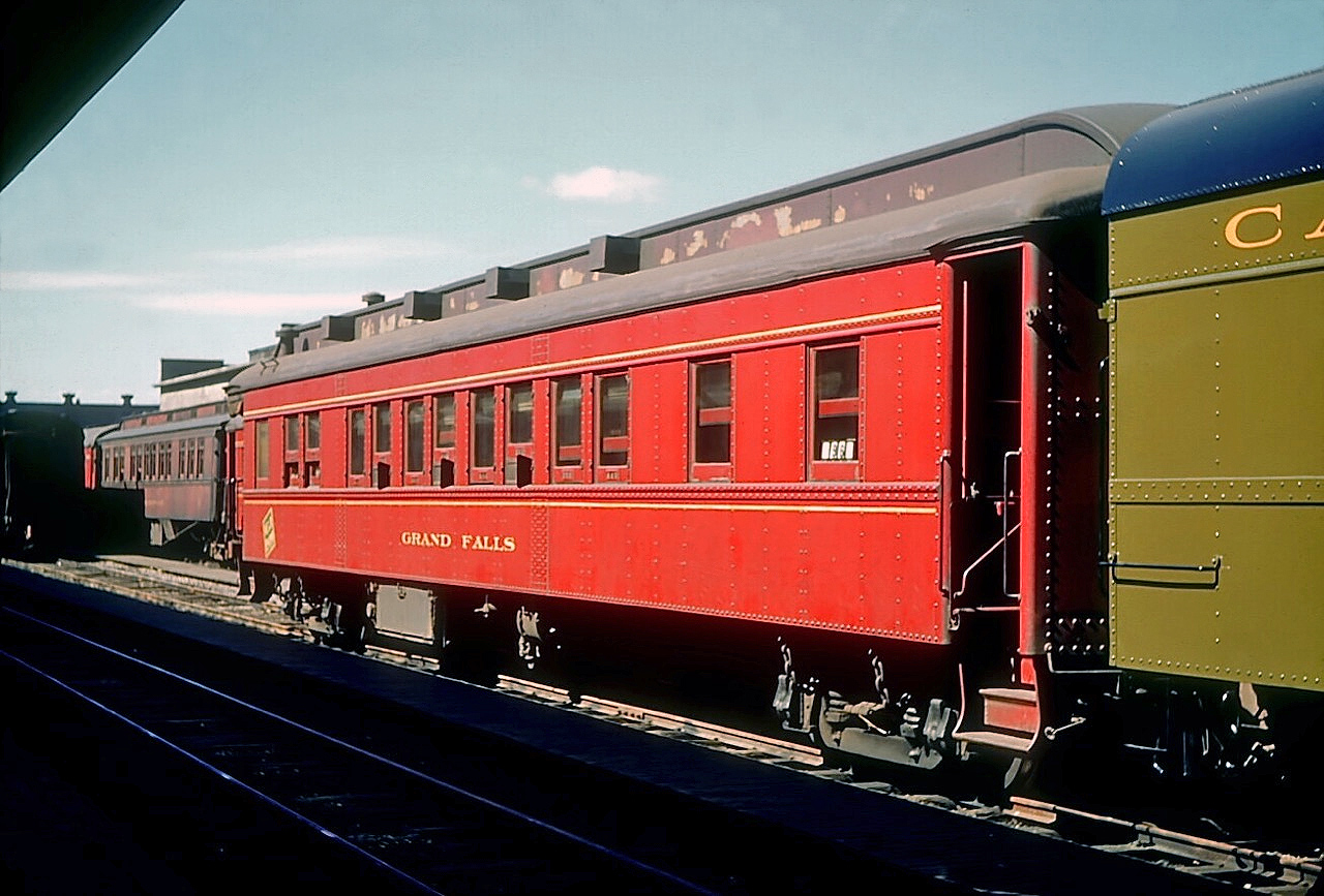 Canadian National Railways sleeping car "Grand Falls". still wearing its Newfoundland Railway colours three years after Newfoundland became Canada’s 10th province, is seen in St. John’s July 29, 1952.  Built by National Steel Car in 1928, it was one of the three oldest sleeping cars in the fleet.  It was fitted with 8 sections and 1 drawing room and, like all Newfoundland Railway passenger cars, was not air-conditioned.  Passengers  in a lower berth could open the lower sash a few inches exposing a fine mesh screen which kept out most, but not all, of the smells and sounds of steam-powered railroading.

[Note: geotagged location not exact]