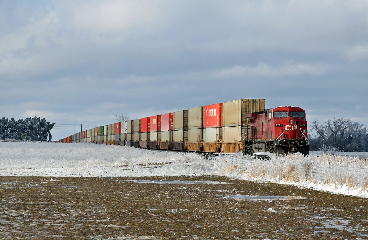 After the Easter long weekend ice storm, CP 112 with CP 9781 and mid-train DP unit CP 8933 sits in the siding track at Baxter after meeting CP 113 (CP 8616, CP 9607 and DP unit CP 8615).  South of Alliston, train 421 is doubling away into the yard at Spence to perform their work and once he is clear, 112 will receive their clearance to depart for points south.  The ice storm which occurred the previous day had blanketed southern Ontario with a layer of ice, with the Alliston/Baxter area being particularly hard hit.  Areas further north must not have fared any better, as evidenced by the damage to the 9781.  If you look closely, you will notice that both ditch lights are damaged, with the lights dangling below the front platform of the locomotive; if they still work, they will not do much good once the train gets rolling!