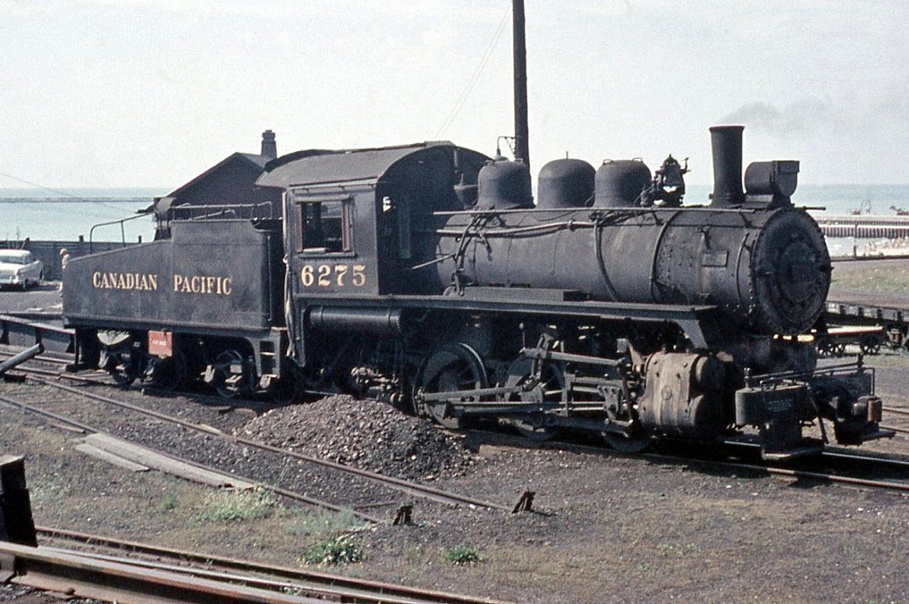 Canadian Pacific Railway 6275, a U3e class 0-6-0 build by CP's Angus Shops in 1912, sits at CP's Goderich terminal facilities in 1958, just ahead of the turntable for the roundhouse.  According to Old Time Trains, the 6275 was the last 0-6-0 anywhere on the CPR system at the time, and made its last run on December 6th of that year. It was briefly replaced by an S3 until the new regular Goderich assigned unit 17 (a new CLC DT2 siderod switcher) arrived. Rather than being cut up for scrap, 6275 is now preserved inside the Huron County Pioneer Museum in Goderich. The CPR's Goderich yard, roundhouse and trackage have all been removed, but the old station survives.