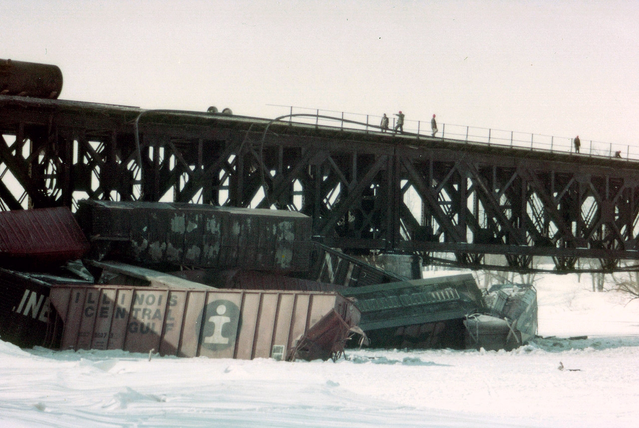 I am throwing this photo out to the viewers of RP in hopes that someone can fill me in on just what this scene was all about. My notes, after now 38 years, have been lost, as well as my recollection of the incident. I believe it was an eastbound Conrail (PC) that derailed. But not sure. Never did see the power. All I got to see was this mess below the Grand River bridge at Cayuga, piled up in the ice. After much looking around, there was really no way to photograph this but go back from where I was and drive up the east side of the river to what was Townline Road E., and walk. It was bitter cold with a strong wind blowing from the NorthWest, and the snow was about a foot deep. I guessed I walked a half mile. Right up the middle of a frozen river. And I noticed I was the only one that did. So came away with several pictures similar to this one. Can anyone shed some light on this wreck? THANKS!