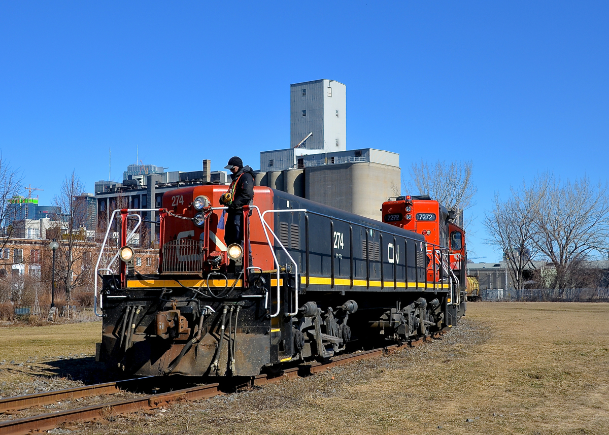 Switching at Robin Hood slug first. Slug CN 274 and GP9 CN 7272 are at Robin Hood mill to pick up 7 empties at the end of East Side Canal Bank Spur. Once a common sight along both sides of the Lachine Canal, trains are now very rare, with Robin Hood mill being the only rail-served client along the length of the entire canal. Barely visible at left behind the mill is the skyline of downtown Montreal.