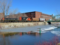 <b>Along the Lachine canal.</b> Slug CN 274 and GP9 CN 7272 have left the Robin Hood mill with 7 empties as they head west along East Side Canal Bank Spur. Once a common sight along both sides of the Lachine Canal, trains are now very rare, with Robin Hood mill being the only rail-served client along the length of the entire canal. The train has just crossed over Charlevoix street, which the crew had to flag.