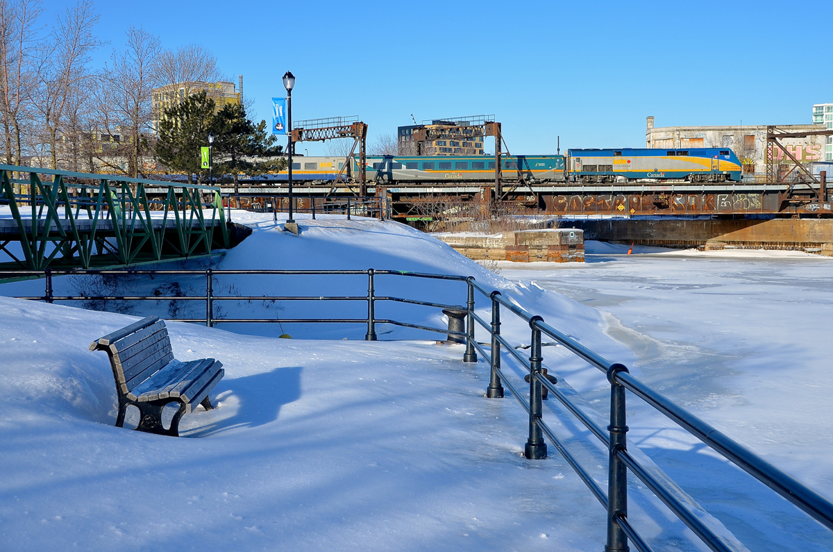 A little too cold for sitting out on a bench. VIA 906 leads VIA 30 from Fallowfield over the frozen Lachine Canal and Peel Basin on a cold morning. At this time of year, I don't think the bench in the foreground sees much use!