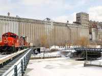 <b>Stopped with grain elevator #5 behind.</b> A CN transfer is about to enter the Port of Montreal with a pair of GP9's (CN 7204 & CN 7246, both very clean and in the current CN paint scheme) with a long string of well cars, with double stacks, single stacks and some empties. The train is stopped over the eastern end of the Lachine canal, awaiting port security and is passing grain elevator #5.