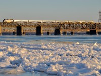 <b>Ice along the river's edge.</b> AMT 1325 leads a deadhead movement from Candiac over the St-Lawrence river during the evening rush hour, on its way back to downtown Montreal. The river still has quite a bit of ice along the shore on the Montreal side of the river.