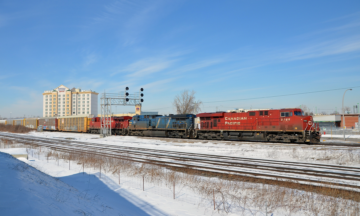 A trio of GE's GE ES44AC's CP 8765 & CP 8916 sandwich GE AC4400CW CEFX 1050 on CP 118 through Dorval. In the foreground is the parallel CN Kingston Sub.
