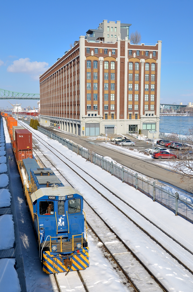 Idling by the old cold storage warehouse. RP20BD POM 1002 is idling with a cut of cars in the Port of Montreal. In the background is right is what once a cold storage warehouse but is now a condominium building.
