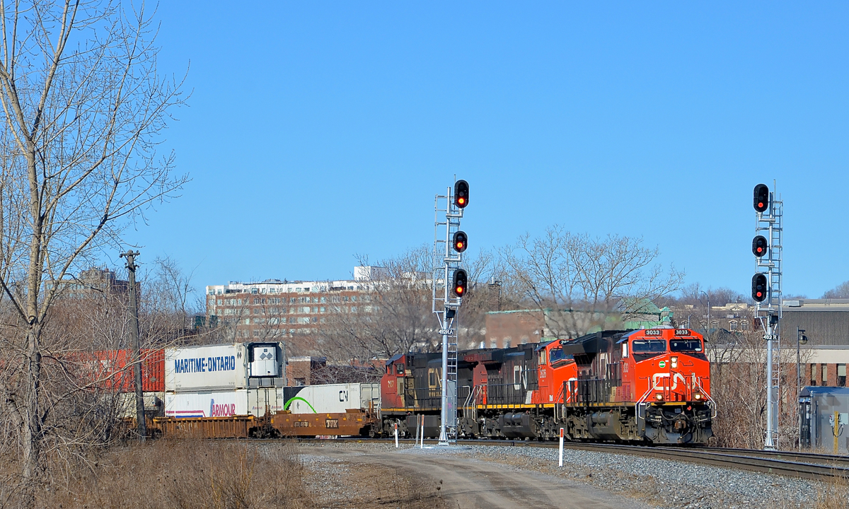 CN 120 around the curve.CN 120 is rounding a curve in the St-Henri neighbourhood of Montreal with a trio of GE's up front, organized newest to oldest. Leading is ET44AC CN 3033 (built in 2015), followed by Dash9-44CW CN 2626 (built in 2000) and CN 2137 (built in 1992 as ATSF 804). ES44AC CN 2809 (built in 2013) is also operating mid-train on this very long 636-axle intermodal train. The head end is passing a relatively new set of signals.
