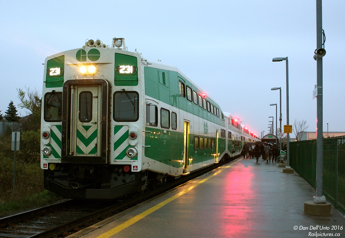 Commuting isn't always pretty, but despite rain, sleet, snow, the resilient commuter will battle traffic and Mother Nature to get to and from the station to catch their train to work (which may or may not be running on time). A comparison can be made to the caveman-esque hunter/gatherer, that must routinely forage the forest for sustenance and battle savage beasts enroute, or starve.

The usual Vaughan commuting suspects are exiting GO Transit train #809, the last of the Barrie line trains, on this bleak rainy evening. Warm buses, cold cars, a jammed up parking lot and evening rush hour traffic await them before sitting down for a warm meal at home. The photographer is posed in the rain at the end of the platform, capturing the routine scene before making his way to a warm YRT D40LF idling nearby. Rebuilt UTDC cab car 231 is on the point of this L10 consist (and MP40 651 on the rear), awaiting the CSA in the "5A" accessible car to close the doors (extinguishing the glare from the red "door open" indicator lights) before departing with a "14L" for the crossing to the north.