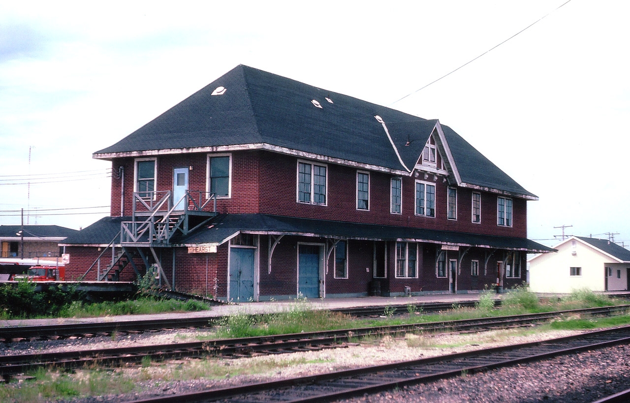 Here is a view looking S/W of the old all-purpose train station (aka: Old Drafty)in Hearst. The town was founded when the National Transcontinental pushed thru in 1913; subsequently the line became CN. Lot of space in this building on account the agent and others lived here, made a lot more sense than trying to commute from elsewhere in the bitter winters. MoW housed here. Express deliveries stored here. Town 'meeting place' at one time. The old building eventually outlived its' usefulness; when I visited here in 1985 the only "service" was a bus connection to Kap, and to the best of my knowledge this building is now long gone, replaced by that mini-sta on the right.