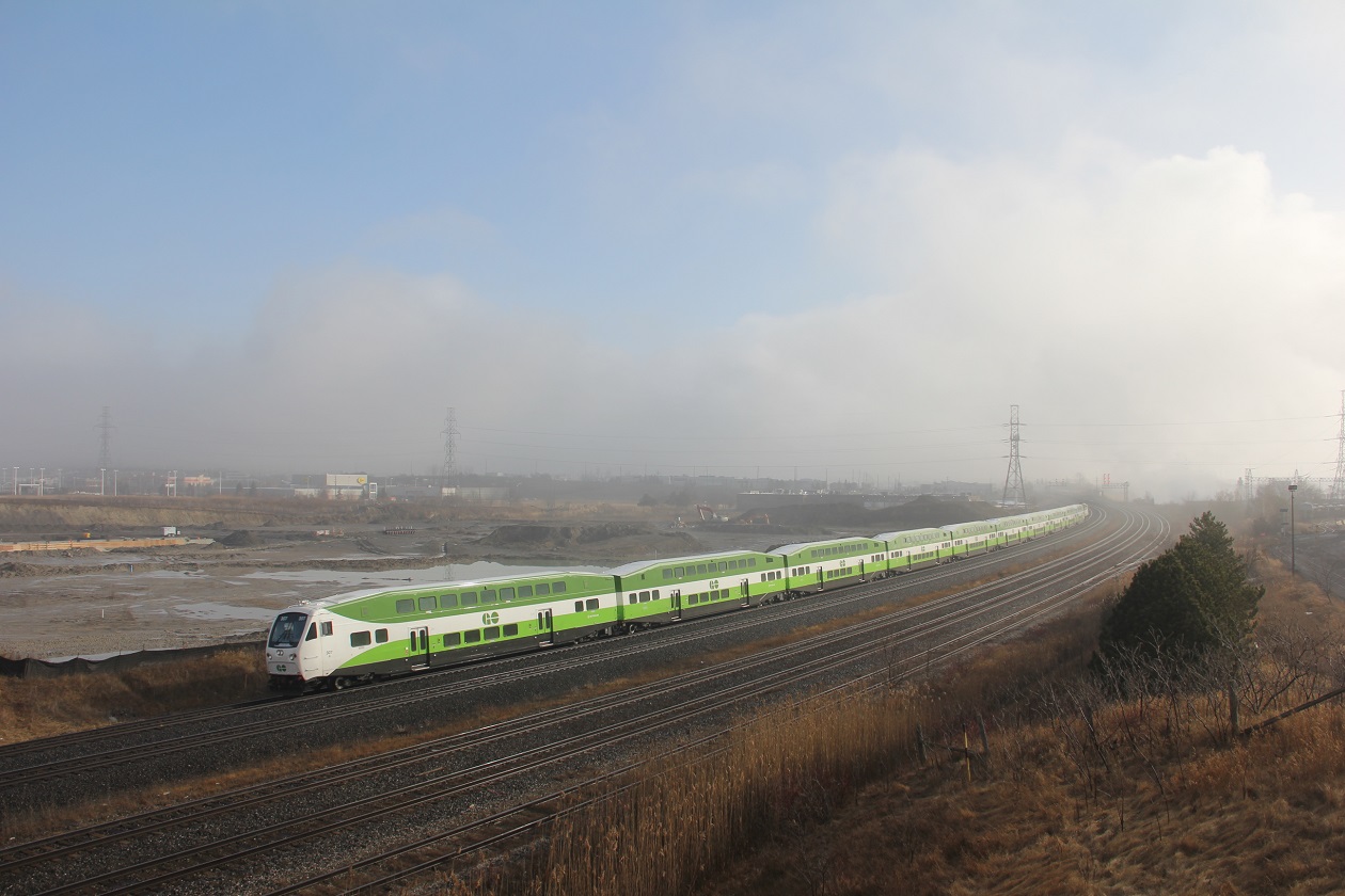 With a record breaking temperature of 16.8 and sunny skies in Toronto,just to the east sadly  not  the same for Whitby. a brief relief from the dense fog, clouds and cold wind off the lake GO 307 and entire train sporting the new normal look proceed west in a small window of early morning sun .