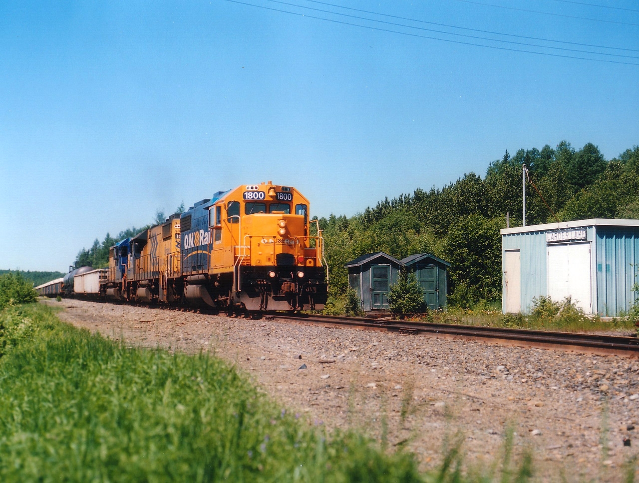 With power I more associate with the now-defunct Northland passenger train, ONR 1800 leads the daily eastbound freight toward Rouyn-Noranda, Quebec and the huge XStrata Copper facility located there. The old box-like Larder Lake station, built in 1924 when Temiskaming & Northern Ontario pushed a rail line thru here, is long gone. MoW shed on the right now sports the old namesign. Not sure of the status of the other two "outhouse" style buildings, but felt them worthy of being visible in the photo. For some odd reason I have always associated outhouses with the North. :o)  Power on this train is ONR 1800. 1804 and 1736. It will return near sundown to Swastika Jct and back down to Englehart. Today's version of this train usually runs with modern SD75I locos.