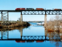 On a beautiful early spring morning, CP #230 Sudbury to Welland steel train is photographed southbound on the Parry Sound trestle, high over the Sequin River mouth. At this time of the year the east side of the bridge is sunlit until around 0830. I am standing on the old CN industrial line bridge, now converted to a walking/biking trail route. And the image is captured using a Mamiya 645E, 400 ISO 120 film. Nice lashup on this train; SOO 6049 leads UP 1972 (x-Cotton Belt) and CP 5625. At this time, counterpart to this daily train was #231. The traffic is now handled by 246/247. In the background one can see the Island tourboat, moored at the Town Dock.