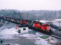 Its a crappy looking day, so out I go. There is always something of interest along the RR on a crappy day. And it is a Sunday. The TH&B "starlite" to me often was earlier on a weekend, and this day it rolled by around the dinner hour. Nice lashup. As you can see, cold and damp; lots of plates and spikes piled up for some maintenance work I have forgotten about..I don't like this sort of clutter in the shot, but looking back; hey, its all railroad related. Engineer waving to a trainwatcher whose name escapes me. Power on this version of the popular train is CP 5725, 5722, TH&B 401, 402, 403, 55 and CP 8791.