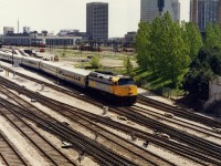 Relatively new F40 6416 leads 5 LRC cars west out of Union Station back when the skyline was relatively uncluttered. In the background a CP SW1200 is pulling some gondolas past the postal delivery building. Back in those simpler times the convention centre had an open air exit corridor along the back of the building you could access to get a decent vantage point. It got closed off a year or two later.