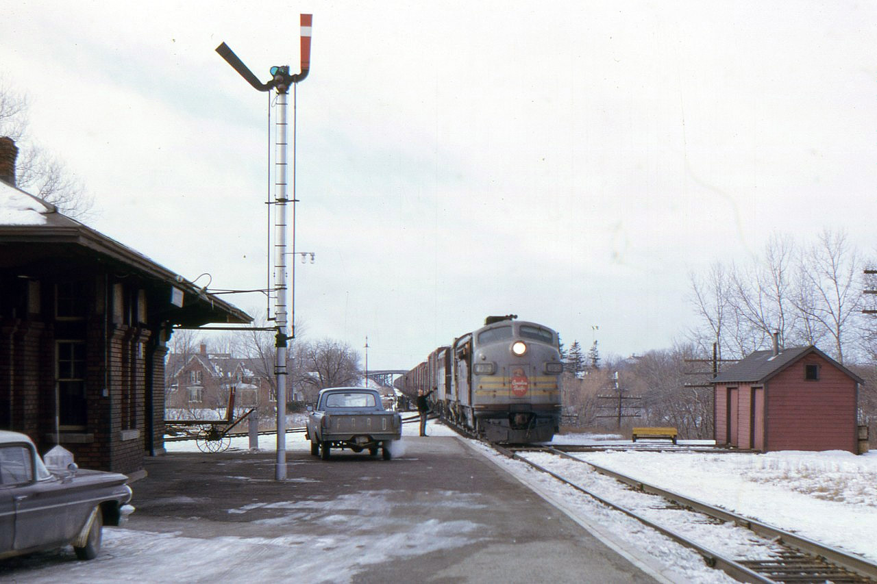 The order board is on yellow and the hoop has just been caught as agent George Borchuk delivers a message to extra 4039 east on Feb. 23, 1966.  The Belleville Sub. has been CTC since 1960, so I'm guessing that train orders are not being used here, but it's a message important enough to put the train order signal on and issue a 'nil' clearance.