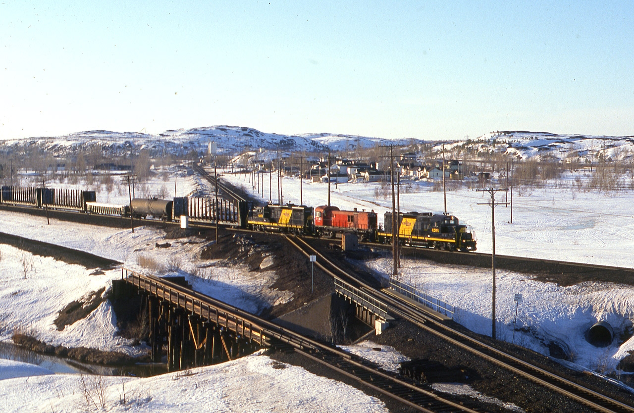 Returning to North Bay after interchange with CP, the Ottawa Valley GP9E 4204, OSRX RS-23 #504 and OV GP9E 4203 run eastward over the CN diamond at Coniston in this very late afternoon in what looks to be a winter day, but is actually the first day of April. That is the town of Coniston right center, and it felt like a lot longer a walk than it was to get to this location after leaving my car in town. 
Not long after this scene, the 4204 was transferred to the Lakeland and Waterways, where it promptly went out of service; the 4203 I have no idea where it ended up and would like to know.......the ORSX 504, former CP 8044 a few weeks previous, now still around in Southern Ontario. Back then, the OSR was an outfit that contracted locos out to mainline and industrial railroads, which explains why 504 was on the loose up here.