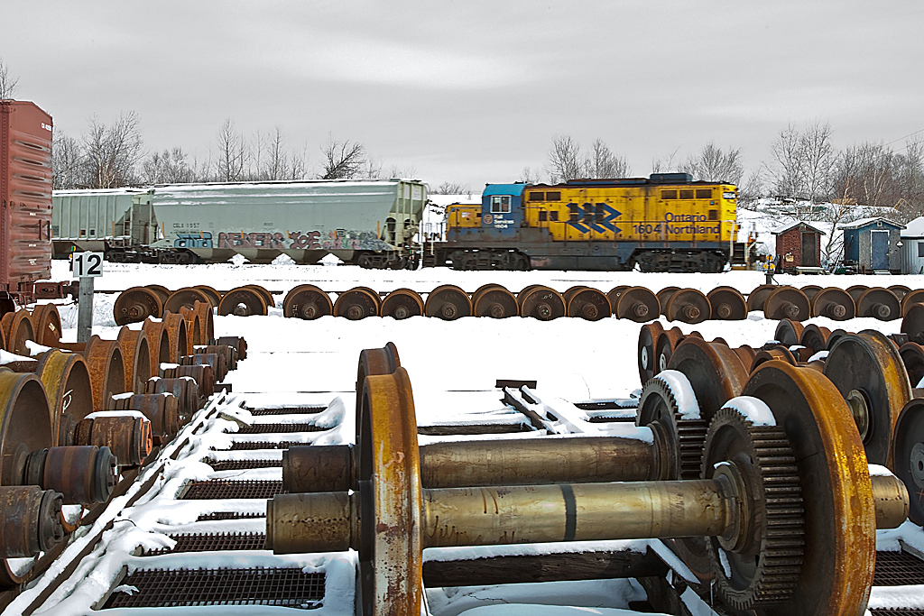 GP9 ON 1604 rumbles past the back lot of the Ontario Northland Shops in North Bay on a blustery day in March of 2011.