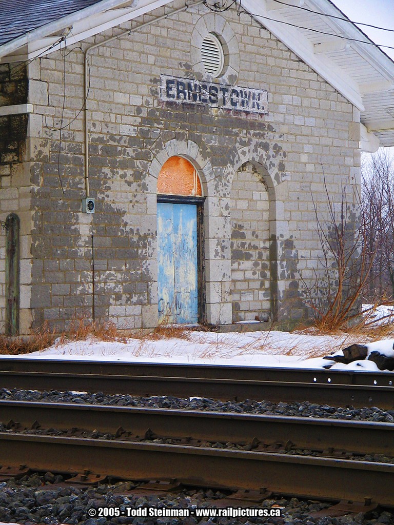 When the Grand Trunk Railway initially surveyed their Toronto - Montreal corridor, they had planned to build their line through the town of Bath. However, the decision was made to build the line 4-5 km north of Bath, and the town never got it's station.

Ernestown did get it's station. Built in typical GTR fashion of stone, it still stands the test of time. Although the trains ignore it's presence, Maintenance crews still used the station when I first visited the site as a kid in the early 80's. Shortly after, the crews left, the station was vacant and damaged by a fire that happened some years earlier. Still stands that way the day I took this photo. Still shows it's architectural detail as one of the few remaining stone stations left that were built in an era that showed prominence and detail, something that the railways of today will not be able to architecturally match.