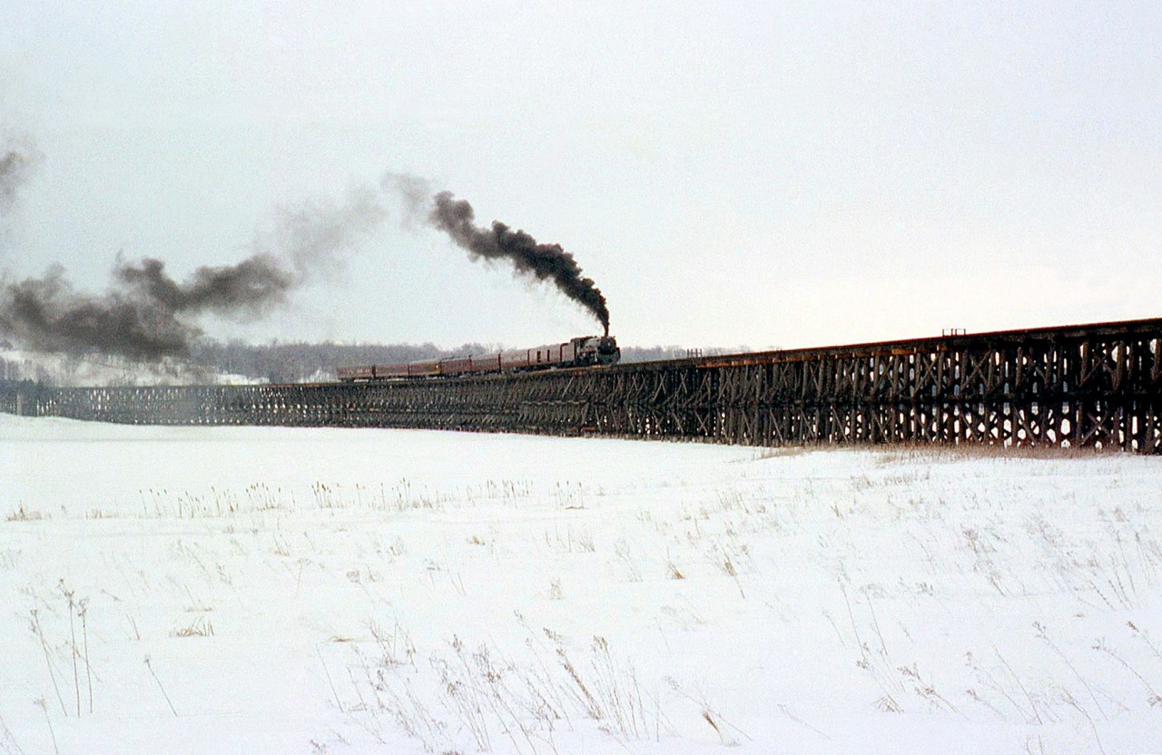Canadian Pacific Royal Hudson 2857, operating on a fantrip from Toronto to Port McNicoll and back, hauls its 7 car consist across the Hog Bay trestle during a photo runby. It was a somewhat dreary March day, but the runby here was a good idea as the Bay was still frozen so one could safely get some photos. Also included on this day was a visit to the Port McNicoll roundhouse for photos of the still active 2-8-0's assigned there, the last regularly assigned steam engines on the CPR. The later (and last) trip in June had better weather for photography but not to photo the trestle (I could not attend that trip).Built in 1908 to span Hog Bay off Georgian Bay, this 2142' long, 40' high wooden trestle allowed the CPR to reach Port McNicoll, where elevators at the port for grain handling, and CPR's fleet of lakeboats produced traffic (summer "Boat Trains" were run up the MacTier to the port until the late 50's). CPR abandoned much of their Port McNicoll Sub including this trestle in 1971, in favour of accessing Port McNicoll over CN's Midland Sub via trackage rights (which crossed underneath the trestle at the south end). It was eventually demolished in 1978.Other photos from the same day:2857 at Union Station: http://www.railpictures.ca/?attachment_id=232693632 at Port McNicoll: http://www.railpictures.ca/?attachment_id=218263722 at Port McNicoll: http://www.railpictures.ca/?attachment_id=22492.
